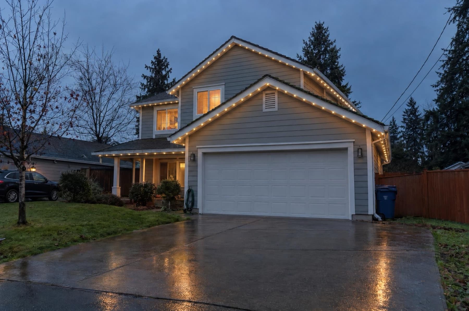 Two-story home with warm-white pebble lights in a white channel along the garage eave and gable